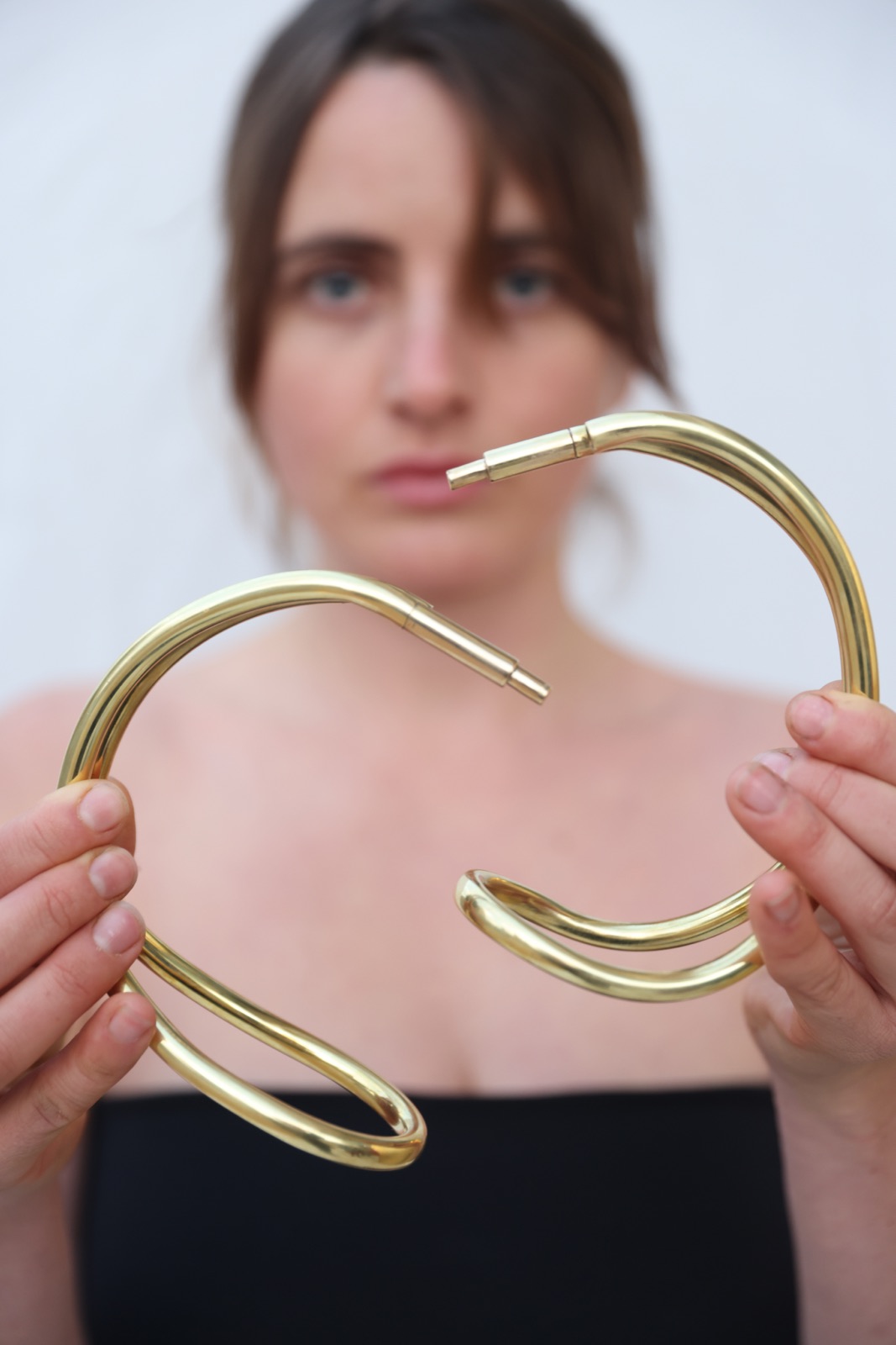 Pair of sculptural brass neckpieces held forward