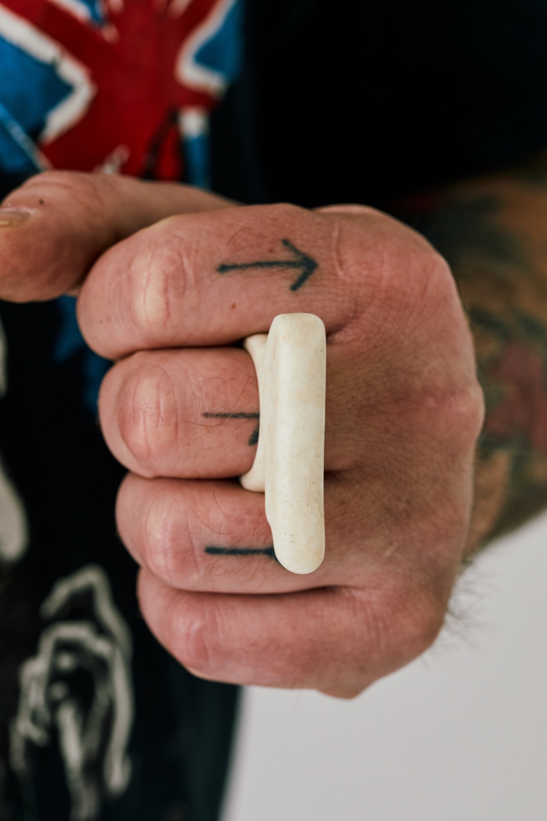 Bone-white wing ring worn on a closed fist