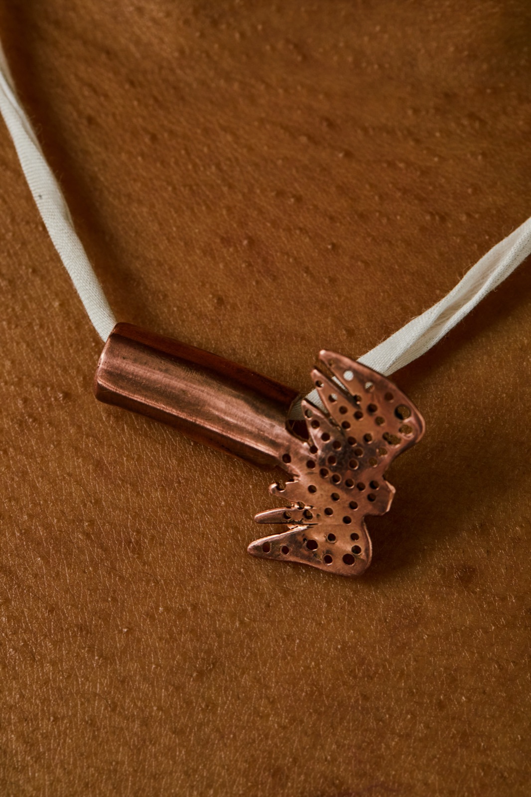 Hammered copper butterfly pendant on a woven cord